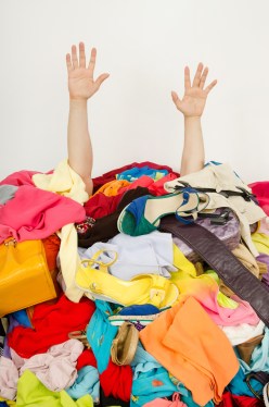 Man hands reaching out for help from a big pile of woman clothes