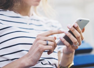 Hipster texting message on smartphone or technology, mockup of blank screen. Girl using cellphone on building castle background close. Tourist female hands holding gadget on blurred summer backdrop